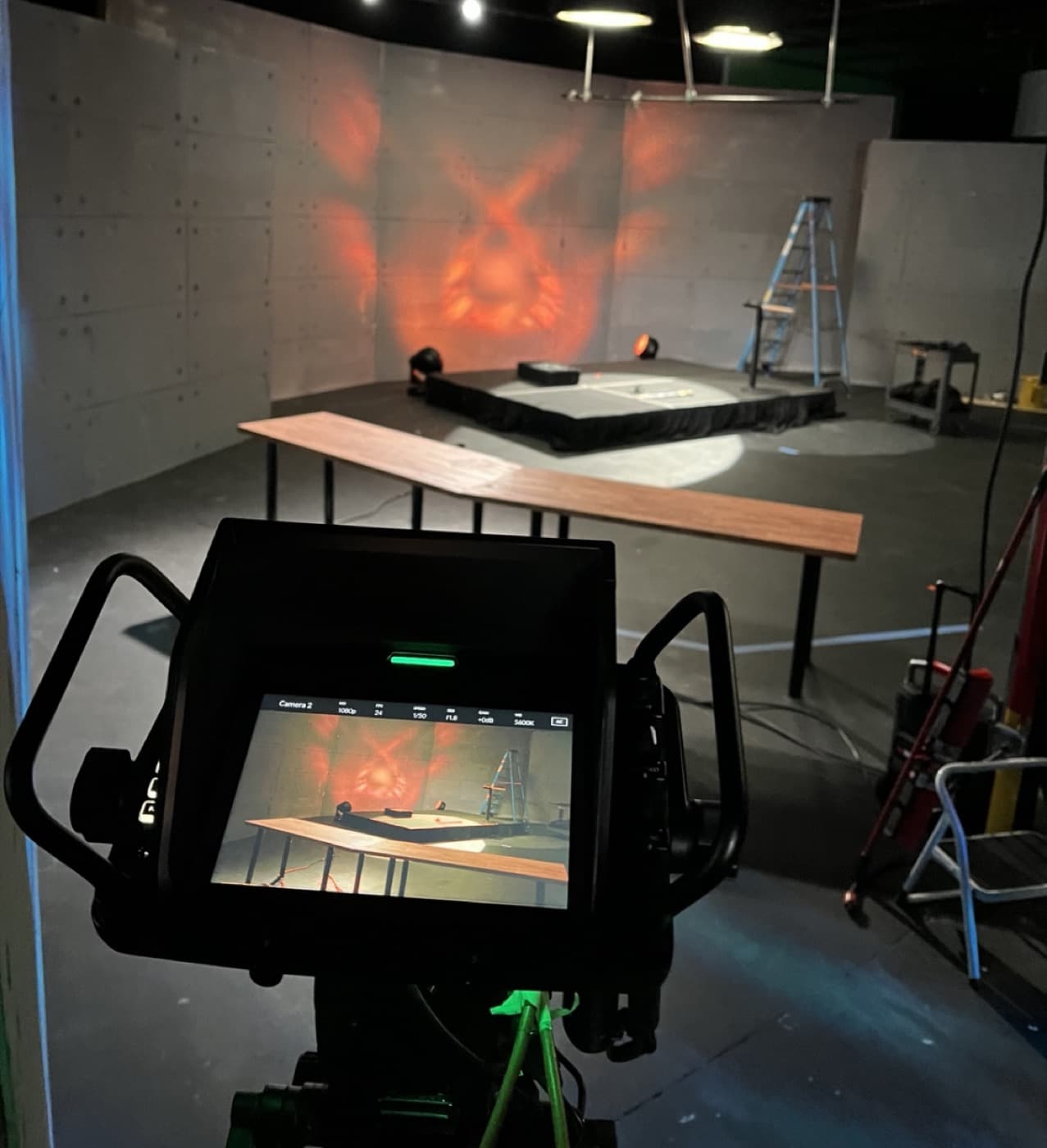 High Arc Media building and lighting a stage set, viewed over a camera monitor