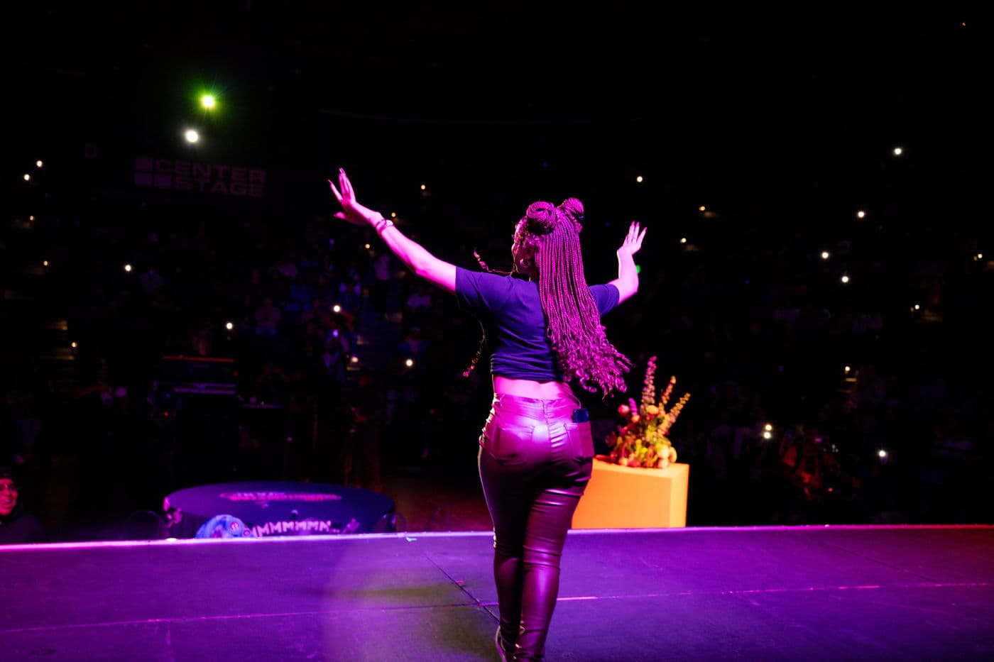Performer on stage under purple lighting at a live event