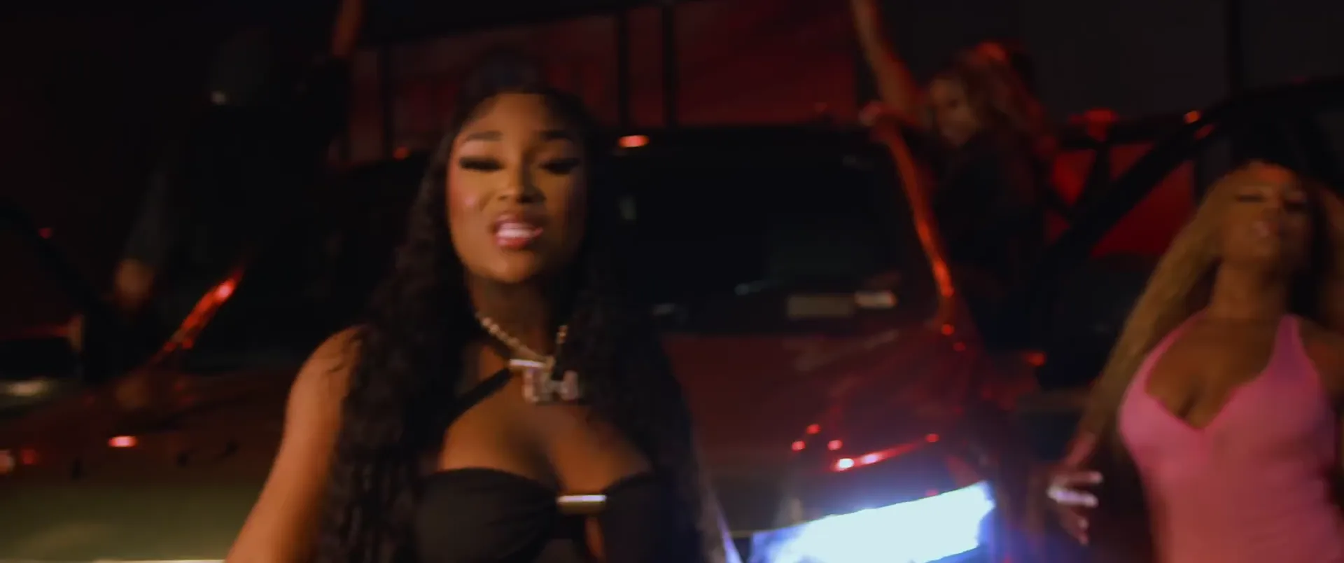A rapper performing to camera in front of a truck at night, from the Lick It video