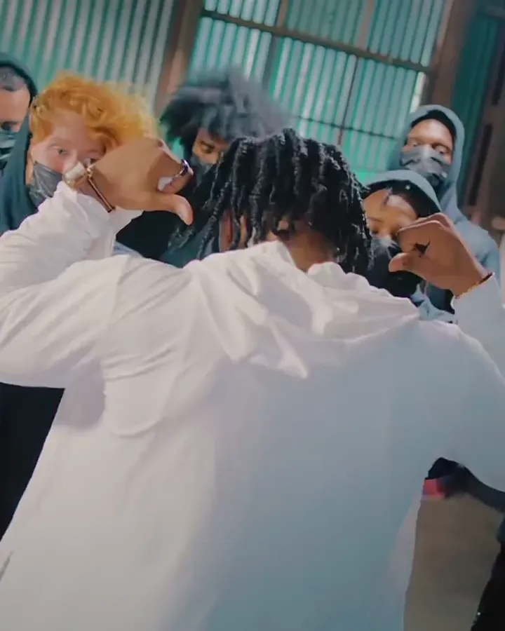 A performer in a white shirt with a crowd in hoodies, from No Call Back